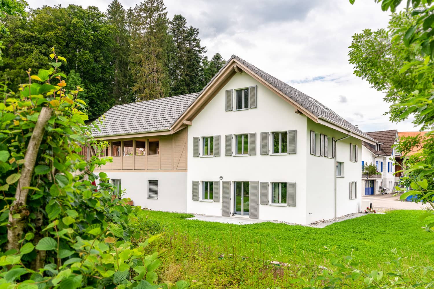 haller-architektur-neubau-bauernhaus-rikenbach Haus mit Satteldach und grüner Wiese